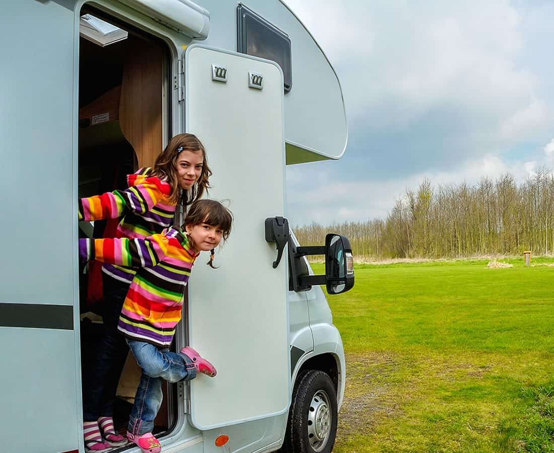 Two girls hanging out the door of an RV