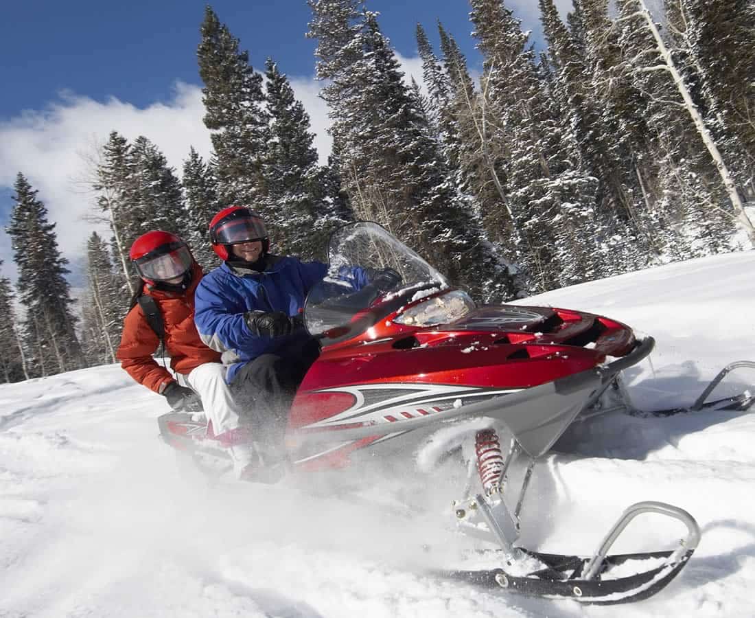 Two people riding a snowmobile.