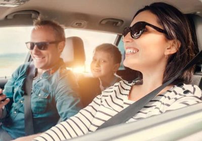 A family smiling while driving in their car