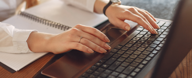 A woman's hands typing on a keyboard