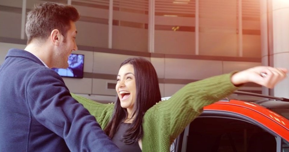 excited couple at a car dealership